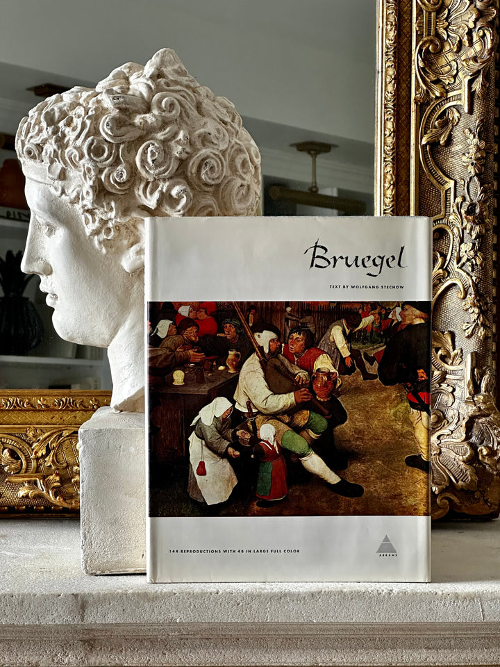 Open book titled "Library Of Great Painters - Bruegel" by Housebound Interiors, featuring artwork and historical paintings.