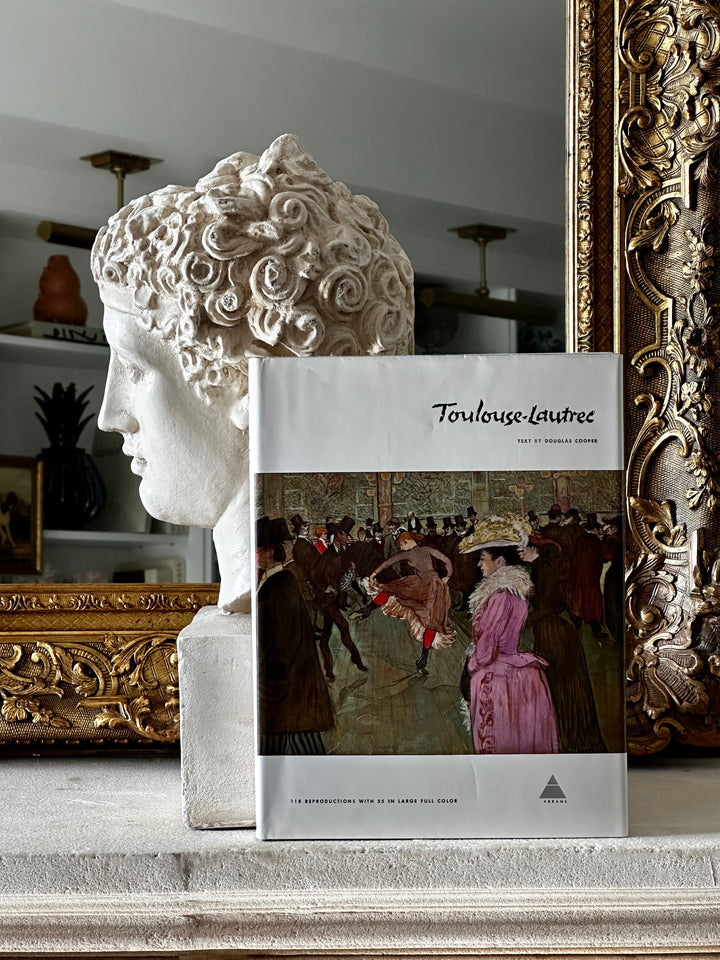 Open hardcover book titled "Library Of Great Painters - Toulouse Lautrec" by Housebound Interiors with colorful illustrations inside.